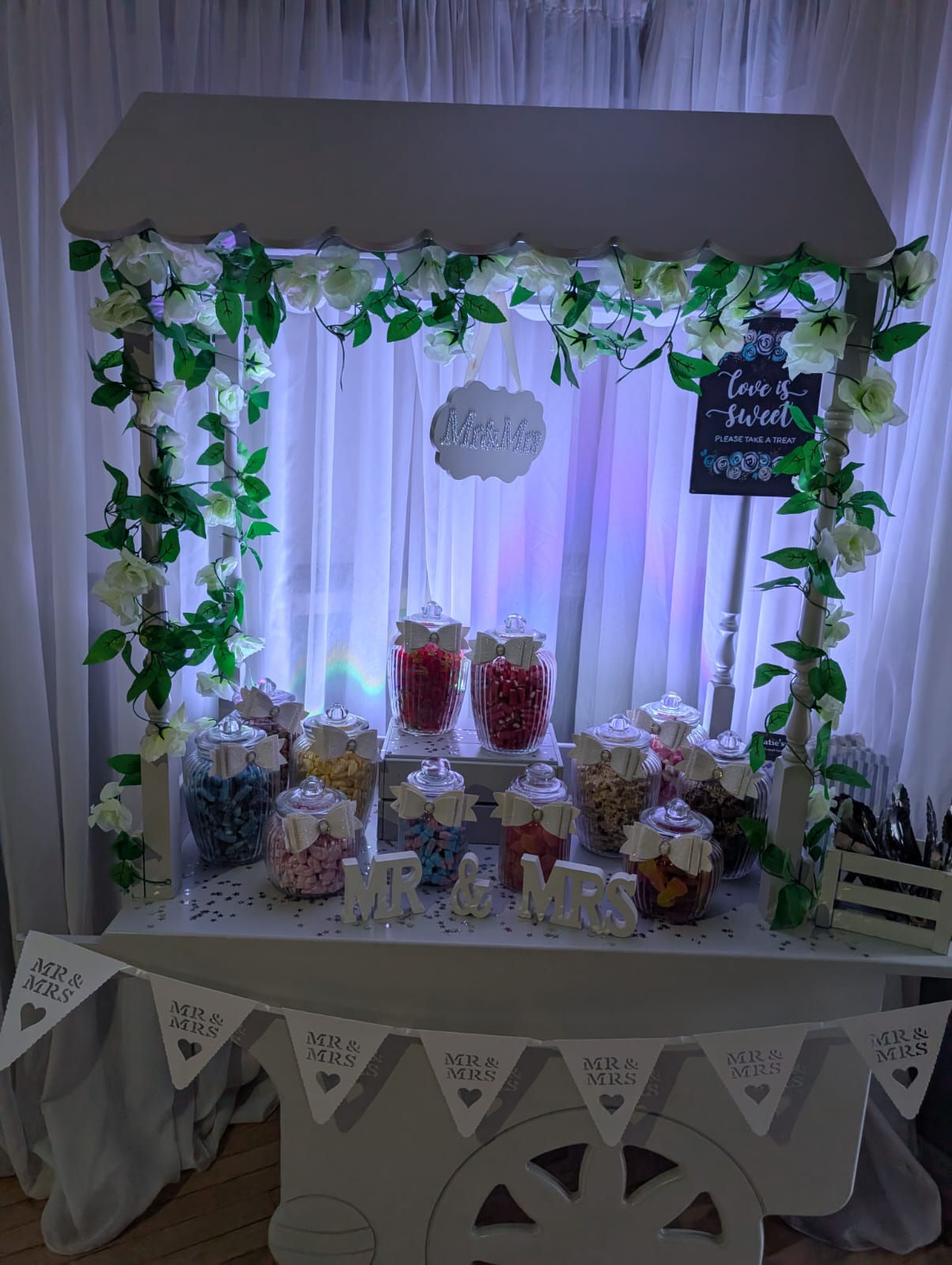 Wedding sweet cart with jars of sweets and flower garland