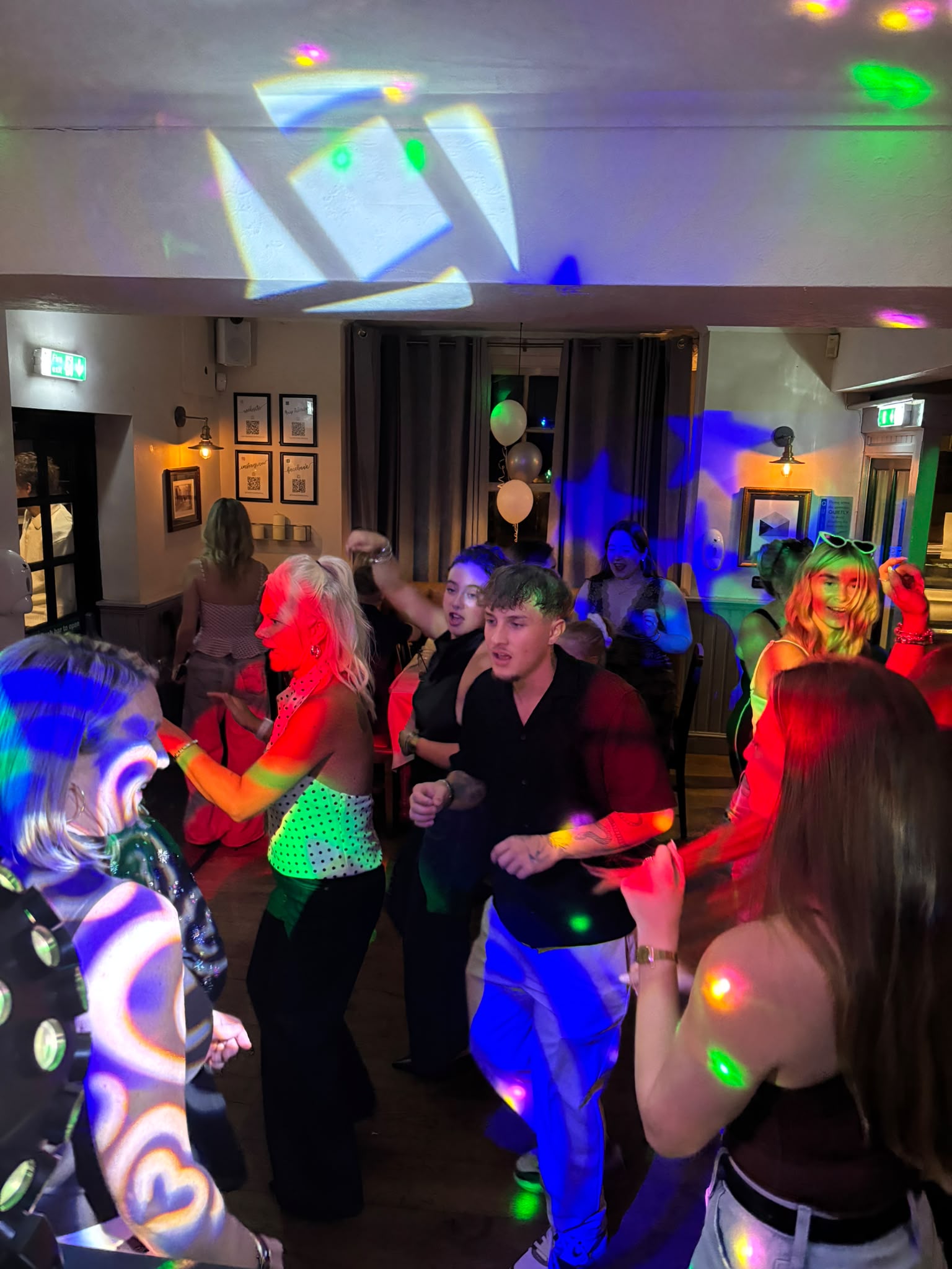 Guests dancing under party lighting at a Sussex pub party