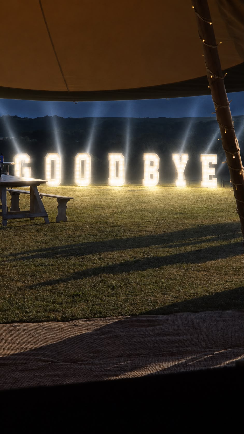 Giant light-up GOODBYE letters outside a tipi at night